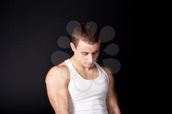 a male in white tank top with strong muscles on the black background