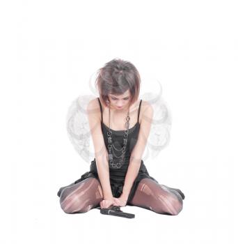 a beautiful brunette model wearing angel wings in sorrow with gun on white
