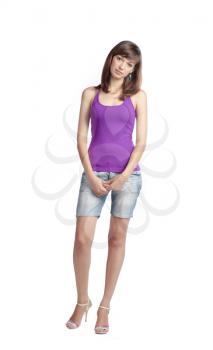 charming brunette women 20-25 years old standing in studio isolated on the white background. Violet tank top, jeans shorts