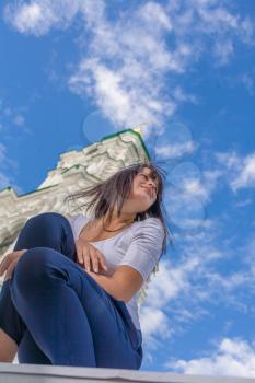Model posing in front of tall historical building and blue sky