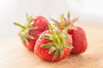 Closeup of ripe strawberries on wooden background - three strawberries on wooden table