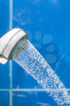 shower head with water drops fallind down from in bathroom on blue background closeup shot spa concept