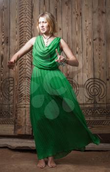 Full body shot romantic blond hair women in long green dress on the background of ancient wood door art posing