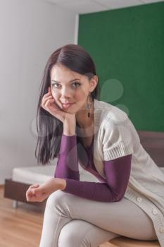 brunette looking at camera, indoors, sitting on the chair, vertical shot