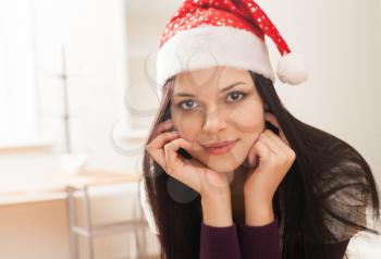 closeup of the face of brunette women in santa hat, indoors