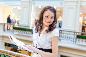 brunette holding book in her hands and looking at camera