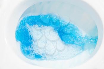 Toilet bowl with blue water flowing