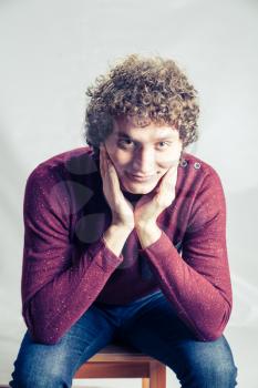 Man weared violet pullover. Curly white man in studio sitting