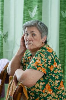 Portrait of a senior woman resting her chin on her hands and looking directly at the camera