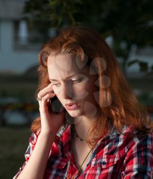 Ginger haired women on cell phone outdoors