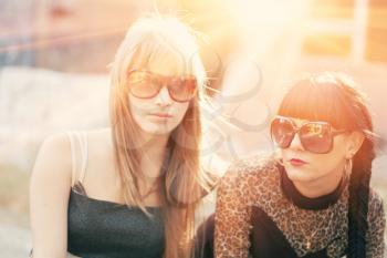 Two female in sunglasses backlit by sunset.