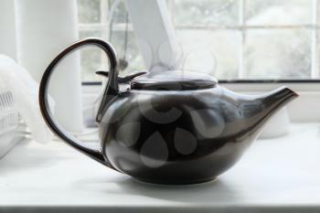 Brown asian teapot on the white windowsill side view