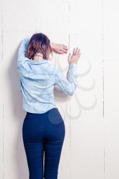 Rear view of a young woman in trendy wear leaning on painted wall with space for text, copy space