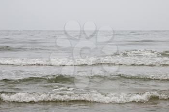 A gray seascape with a waves on against the gray sky
