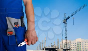 Royalty Free Photo of a Worker Holding a Tool With a Building in the Background