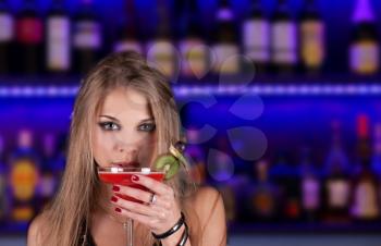 Girl with cocktail on bar counter background
