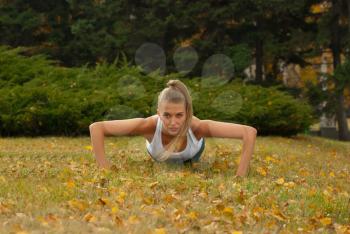 Beauty female doing push ups in the park
