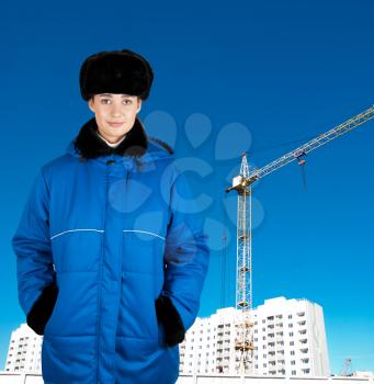 Young architect-woman wearing protective winter cloth standing on the building background