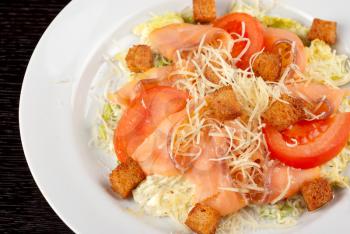 Salad of lettuce, chinese cabbage, tomato, garlic rusk, parmesan cheese, sauce and smoked salmon filet