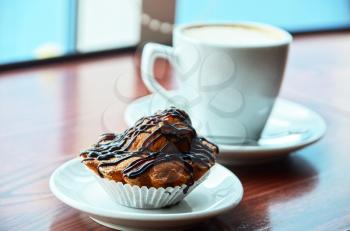Chocolate muffins with and coffee cup on orange table