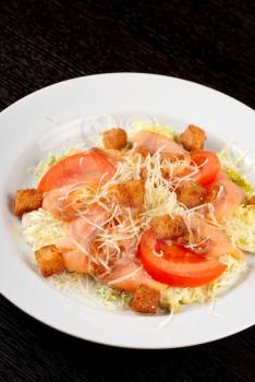 Salad of lettuce, chinese cabbage, tomato, garlic rusk, parmesan cheese, sauce and smoked salmon filet