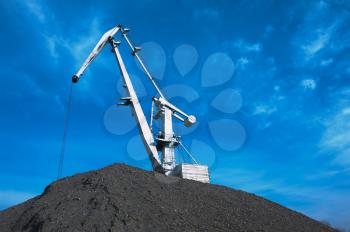 crane at heap of gravel on blue sky background