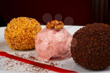 three scoops of ice cream desserts decorates with walnuts and chocolate