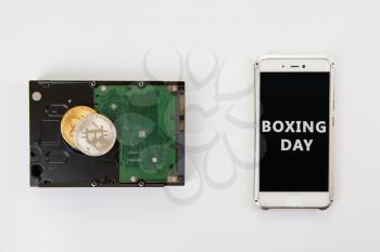 Bitcoin coins on the HDD and phone with Boxing day sign