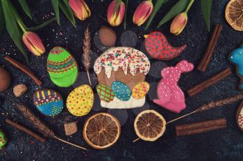 Tulips and gingerbread cookies on darken concrete background for Easter.