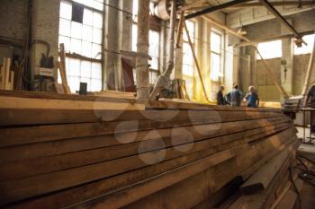 Stack of wooden blanks at the sawmill. Workers on background.