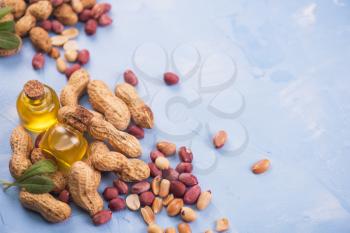 Natural peanuts with oil in a glass jar on the blue concrete background