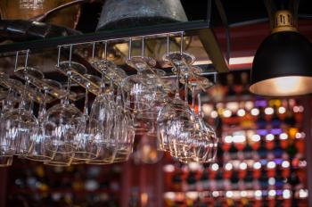 Clean washed glasses hanging over a bar rack