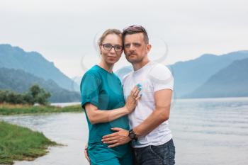 Man and woman couple portrait on Teletskoye lake in Altai mountains, Siberia, Russia. Beauty summer day.