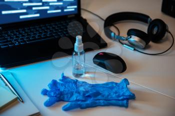 Sanitizer anti virus spray with protecive gloves on the working table with laptop, mouse, headphones. Personal hygiene concept. Concept of quarantine for coronavirus and working from home.