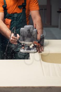 Stone sink furniture production. Worker polishes the surface of the sink with a grinder