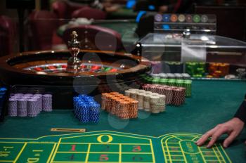 Casino, gambling and entertainment concept - roulette table and stack of poker chips