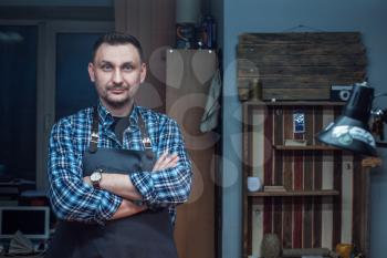 Man working with leather textile at a workshop. Male portrait. Concept of handmade craft production of leather goods.