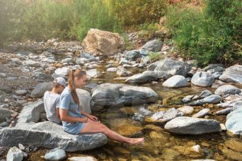 Woman and her son sitting on the rock of mountain river in Altai mountains.