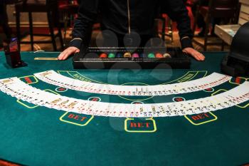 Professional croupier during cards shuffle in the casino