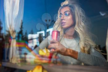 Fast food and leisure concept - beauty young blonde woman eating a fried potato and soda water