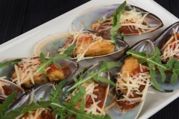 Cooked mussels with sauce cheese and arugula