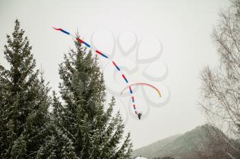 Paraglider is flying in the sky in the Altai winter mountains.