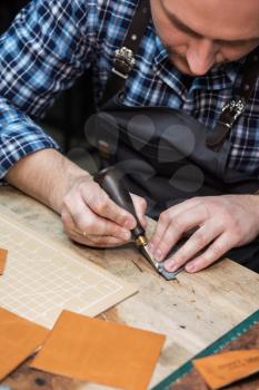 Man working with leather textile at a workshop.