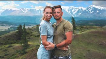 Romantic couple in the mountain, in Altai Mountains. Happy man and woman hug on the background of a mountain glacier, smiling and and look into the camera