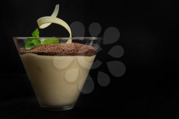Delicious Italian dessert tiramisu, on a black wooden background decorated with mint leaf, with copy space.