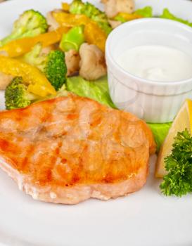 Tasty dish of salmon steak with vegetables and sauce