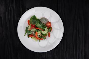 Fresh vegetable salad of cucumbers, tomatoes, raddish, bell pepper, basil and olive oil.