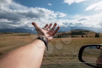 Close up of male traveler hand in auto relaxing and enjoying road trip in Altai mountains Summer vacation and road trip concept.
