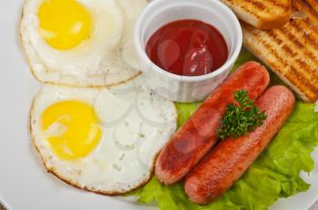 Fried eggs with sausages, toasts, greens and sauce