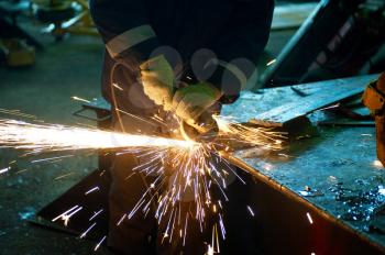 worker welding metal with sparks at factory